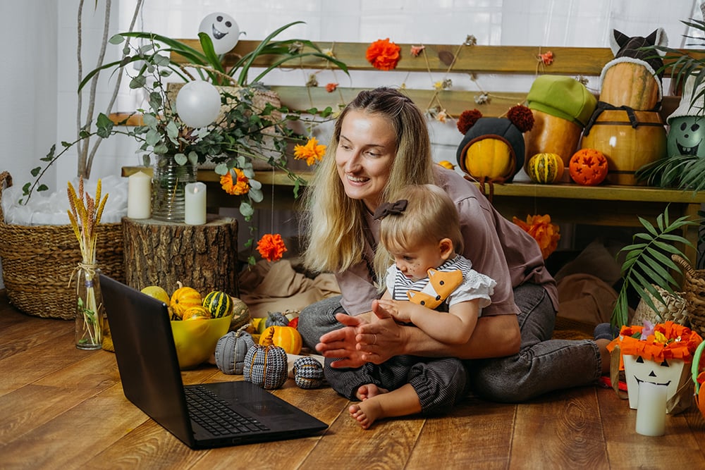 Holidays in the Time of COVID. Happy family, mother and baby celebrating Halloween via internet